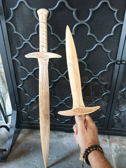 Hand holding up wooden toy sword